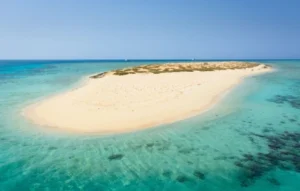 Vue aérienne d'une île de sable blanc entourée d'eau turquoise et de récifs coralliens à Hurghada, Égypte.