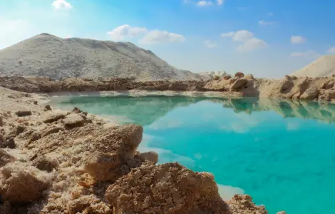 Vue rapprochée d'un lac de sel à l'Oasis de Siwa avec une eau cristalline d'un bleu électrique et des cristaux de sel blancs