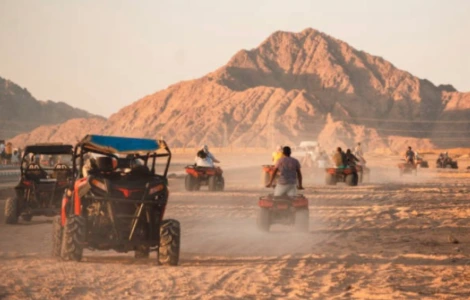 Groupe de touristes en randonnée quad au pied des montagnes du désert égyptien.