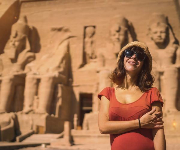 A young tourist in red dress at the Abu Simbel Temple in southern Egypt in Nubia next to Lake Nasser. Temple of Pharaoh Ramses II