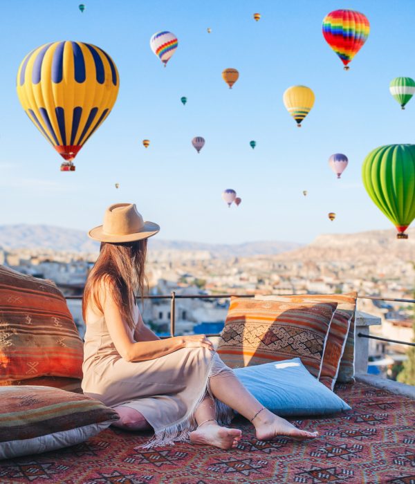 Young woman in Cappadocia. Woman on a rooftop with air balloons in Goreme in Cappadocia, Turkey