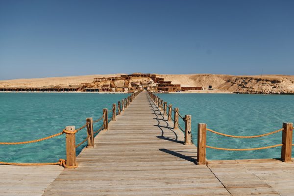 Majestic view of wooden bridge that is on the sea. Island far away.